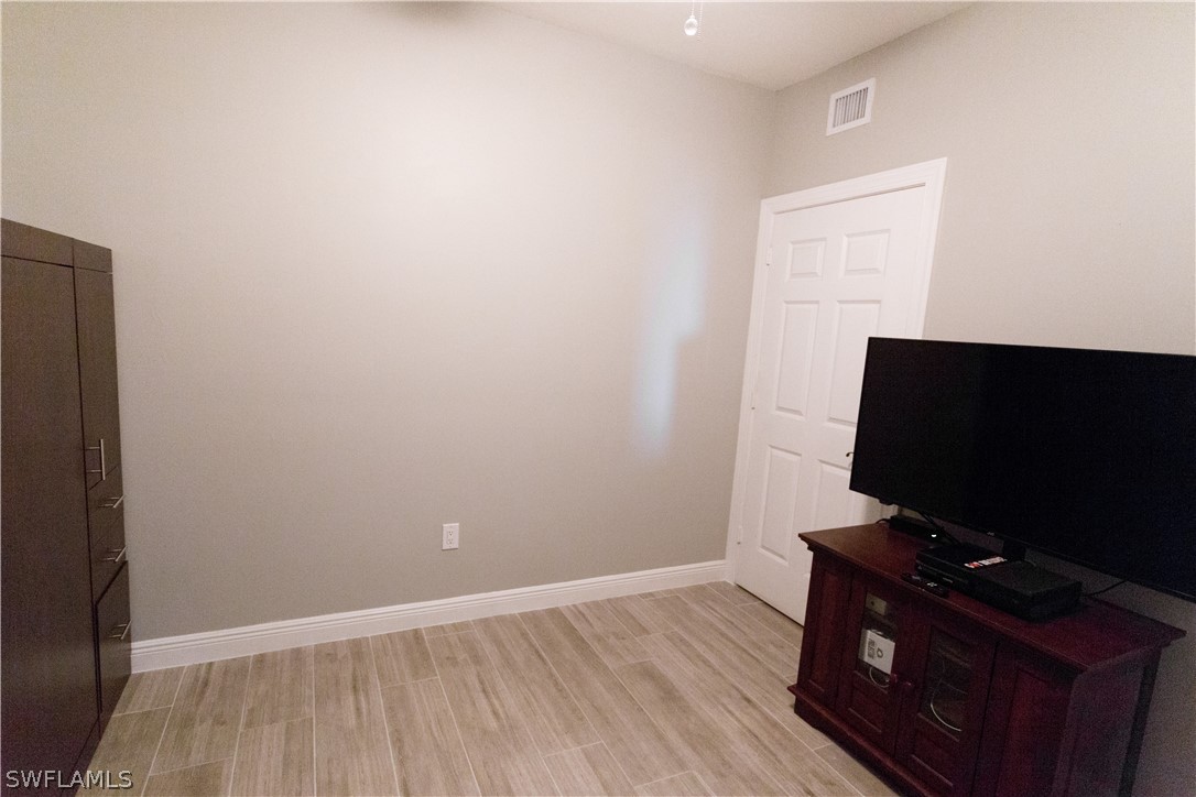 2745 First Street, Unit 1306 Fort Myers, FL 33916 - Photo 18 of 34 a room with wooden floor and flat screen tv