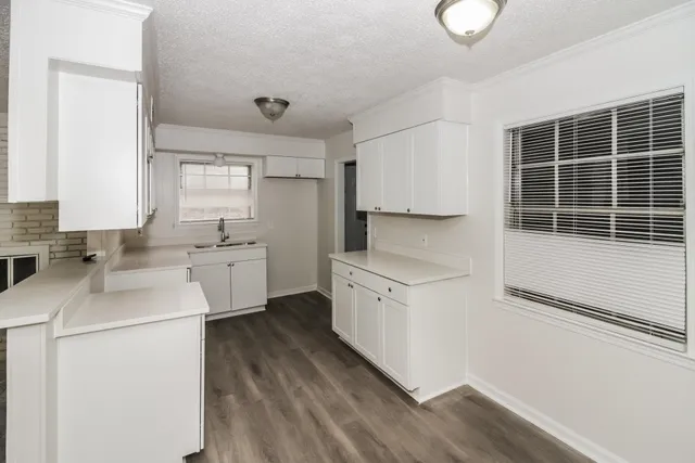 a kitchen with white cabinets and sink