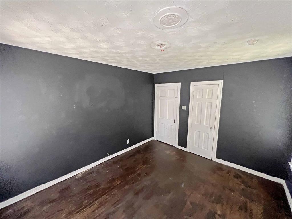 1010 Winters Street Dallas, TX 75216 - Photo 12 of 20 Dark-painted walls with white trim, featuring two paneled doors and exposed wood flooring