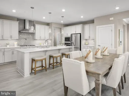 a kitchen with stainless steel appliances granite countertop a dining table chairs refrigerator microwave and cabinets