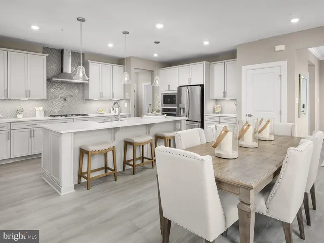 a kitchen with stainless steel appliances granite countertop a dining table chairs refrigerator microwave and cabinets