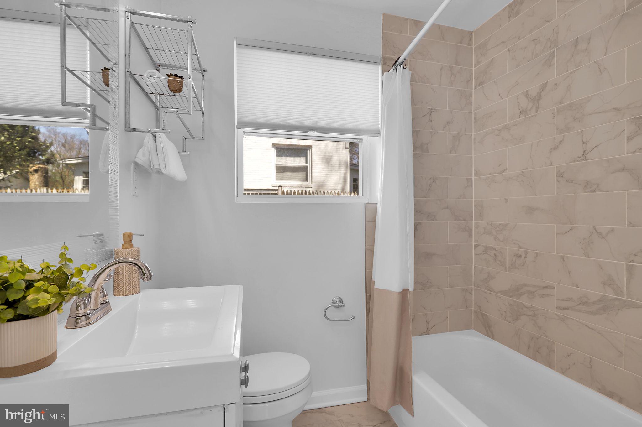 1009 Stirling Road Silver Spring, MD 20901 - Photo 13 of 33 a bathroom with a sink a mirror a toilet and bathtub