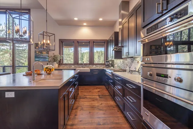 a large kitchen with stainless steel appliances a sink stove and cabinets