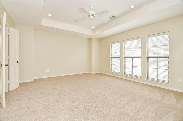 an empty room with windows and chandelier fan