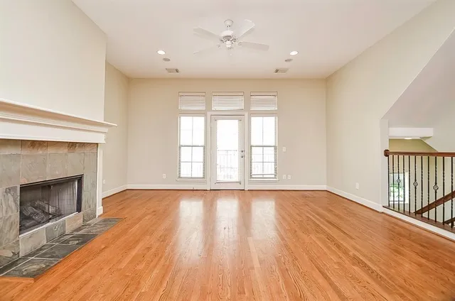 a view of an empty room with wooden floor fireplace and a window