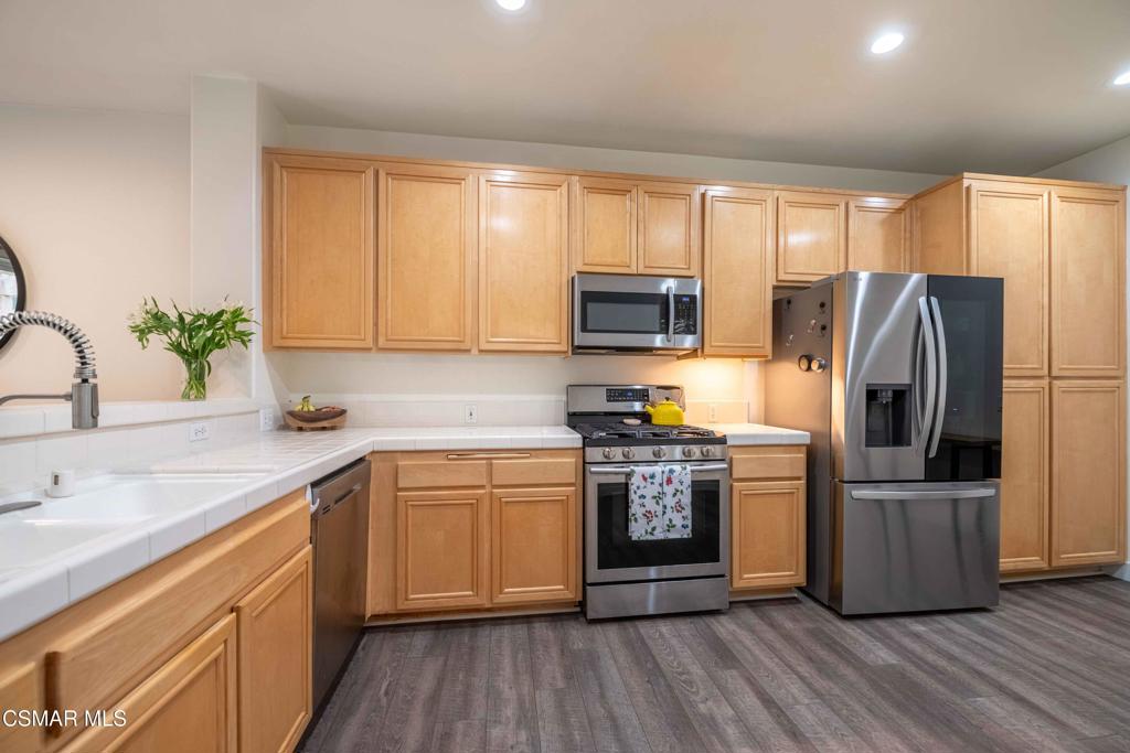 580 Fenwick Way, Unit C Simi Valley, CA 93065 - Photo 11 of 39 a kitchen with stainless steel appliances granite countertop a refrigerator a sink dishwasher a stove with wooden floors and cabinets