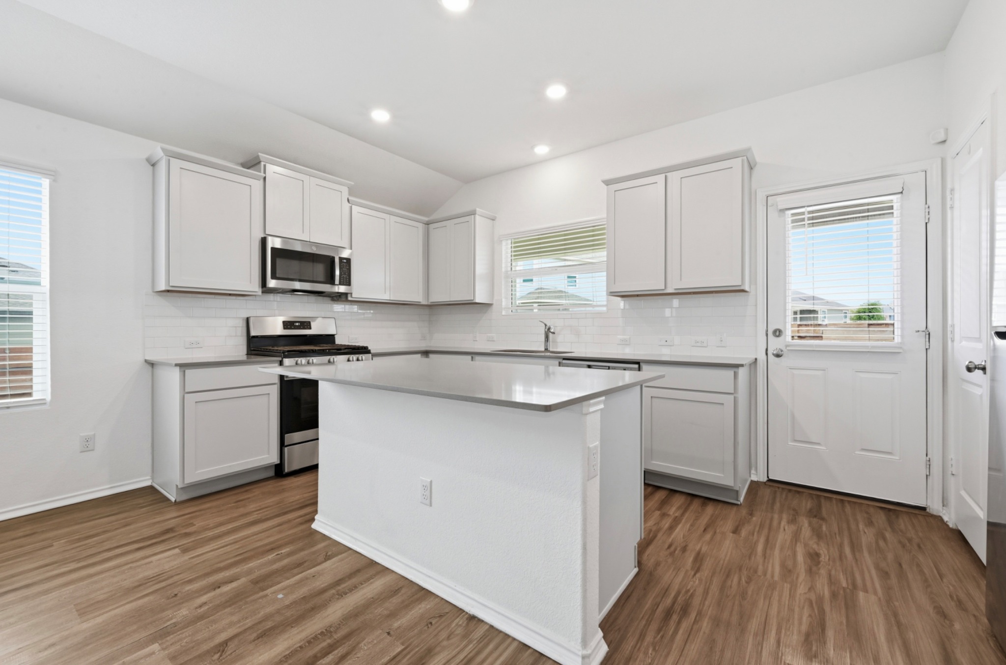 388 Barcelona Kyle, TX 78640 - Photo 10 of 26 a kitchen with kitchen island granite countertop a sink cabinets and wooden floor