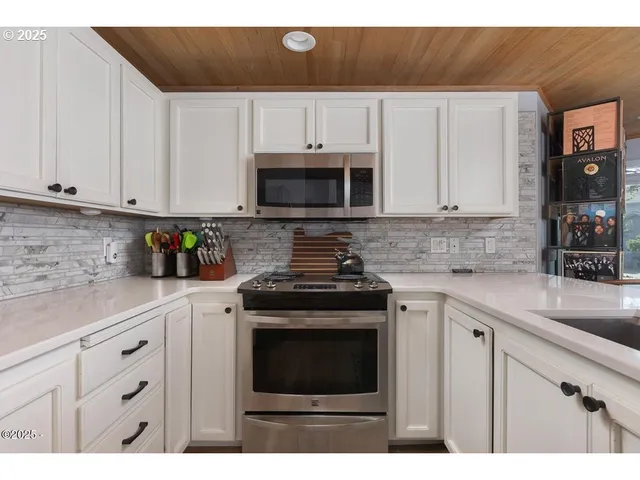 a kitchen with granite countertop white cabinets and stainless steel appliances