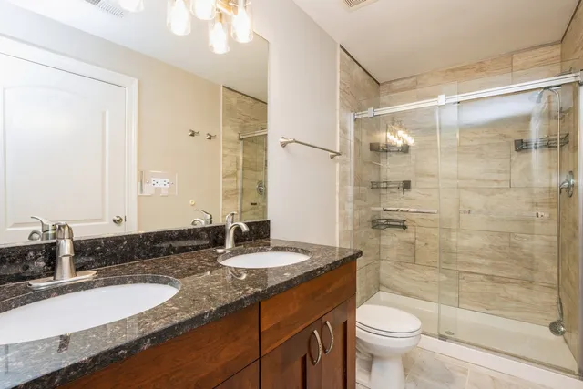 a bathroom with a granite countertop sink toilet a mirror and shower
