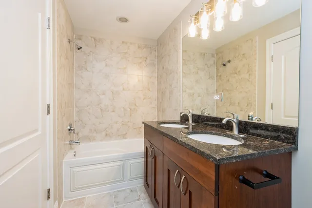 a bathroom with a granite countertop sink tub and a mirror