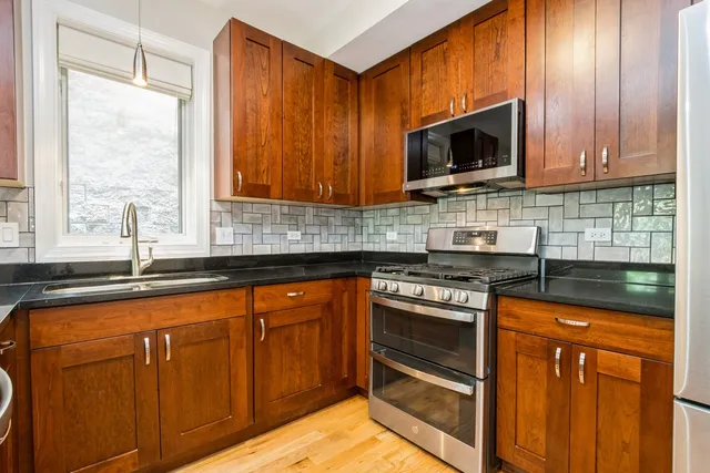 a kitchen with stainless steel appliances granite countertop wooden cabinets and a stove top oven