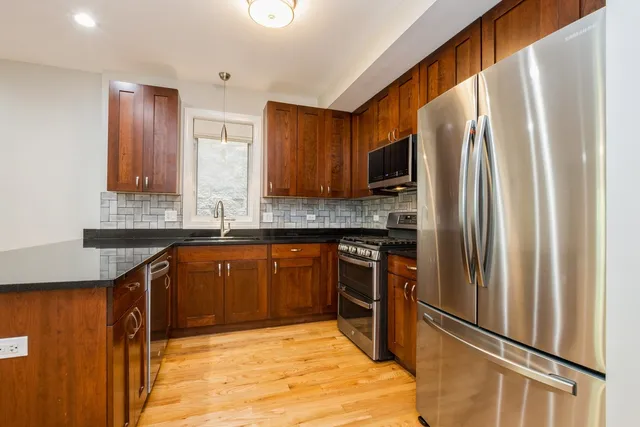 a kitchen with stainless steel appliances granite countertop a refrigerator and a sink