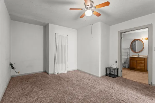 a view of a livingroom with a fireplace a ceiling fan and wooden floor