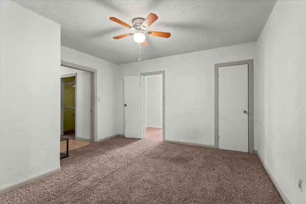 an empty room with closet and a chandelier fan
