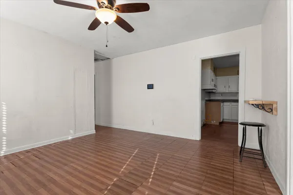 a view of empty room with wooden floor and ceiling fan