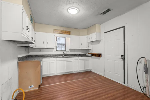 a kitchen with stainless steel appliances granite countertop a refrigerator sink and white cabinets with wooden floor