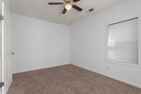 an empty room with a window and a fan