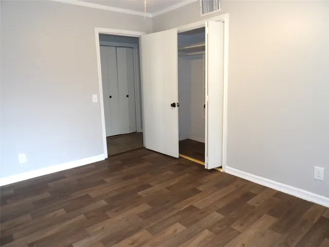 an empty room with wooden floor & closet area
