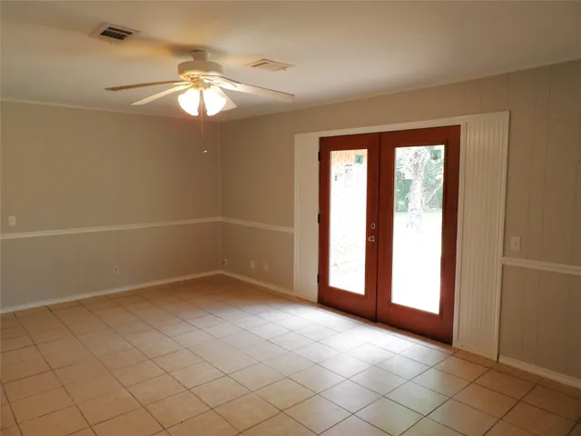 en empty room with windows and chandelier fan