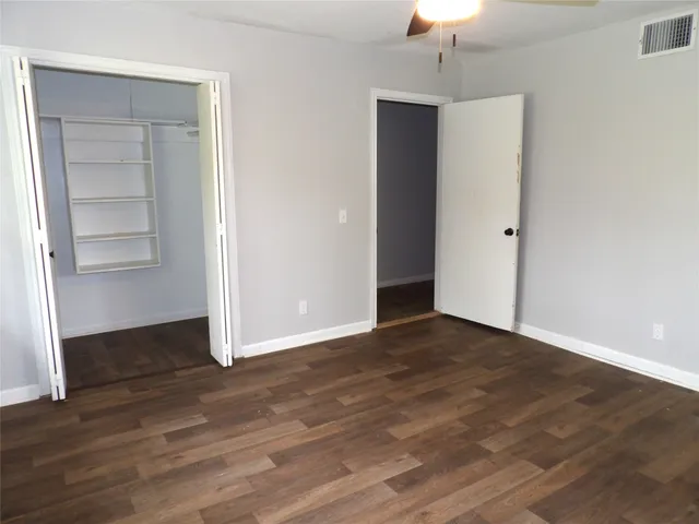 a view of an empty room with wooden floor and closet