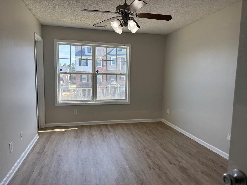 6370 Olmadison Place Atlanta, GA 30349 - Photo 11 of 15 an empty room with wooden floor ceiling fan and windows