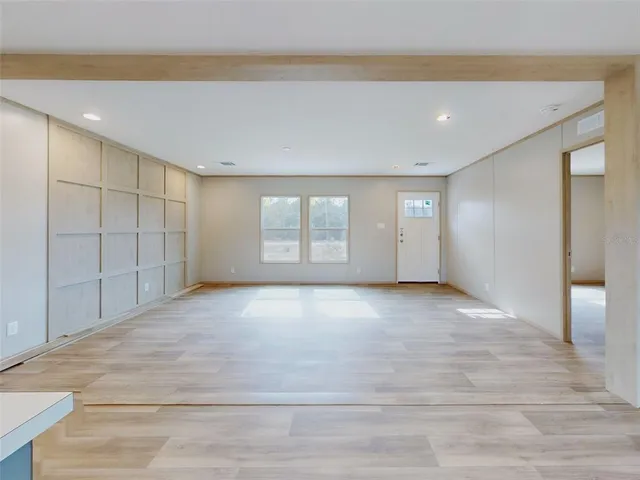 a view of an empty room with window and wooden floor