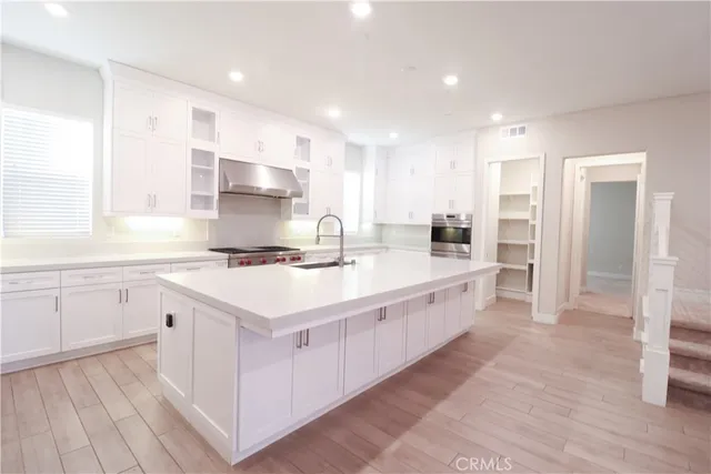 a large white kitchen with a large counter top and stainless steel appliances