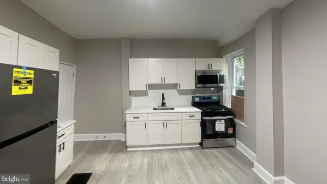 a kitchen with a sink a stove top oven and white cabinets