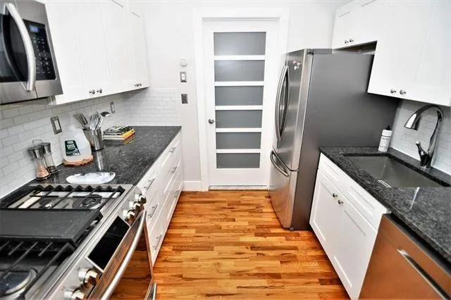 a kitchen with stainless steel appliances granite countertop a refrigerator and a stove