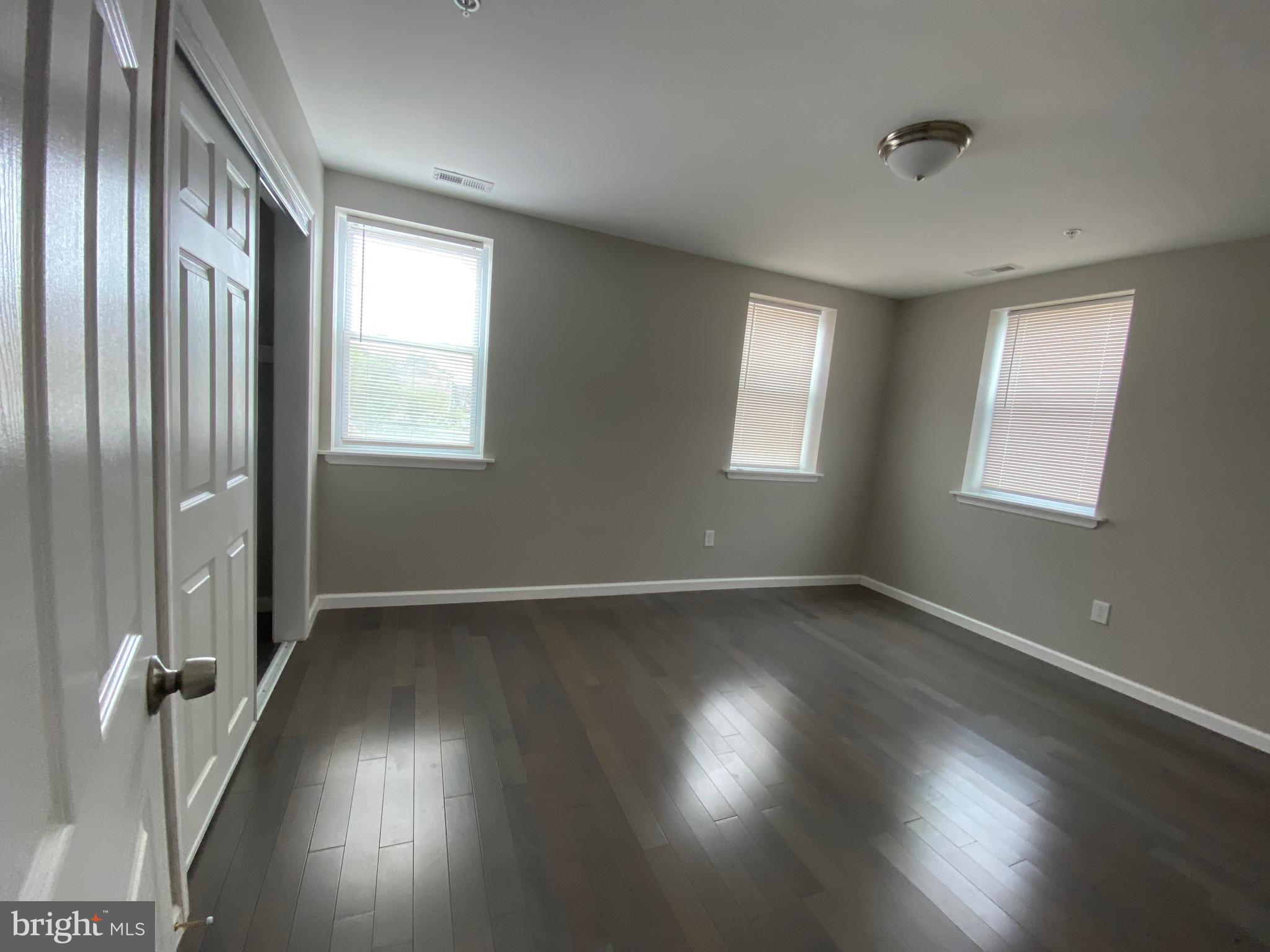 447 Diamond Street, Unit 2 Philadelphia, PA 19122 - Photo 12 of 18 an empty room with wooden floor and windows