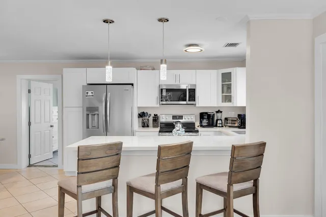a kitchen with stainless steel appliances kitchen island granite countertop a refrigerator a stove a microwave oven a sink with island chairs and white cabinets