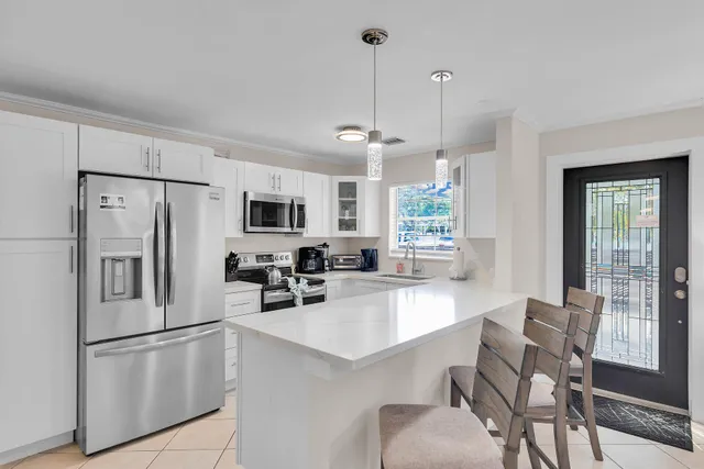 a kitchen with stainless steel appliances granite countertop a refrigerator a stove a sink a dining table and chairs