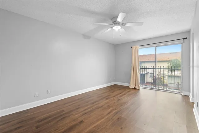 an empty room with wooden floor fan and windows