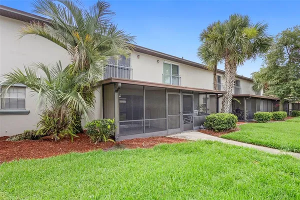 a view of a house with a yard and palm trees