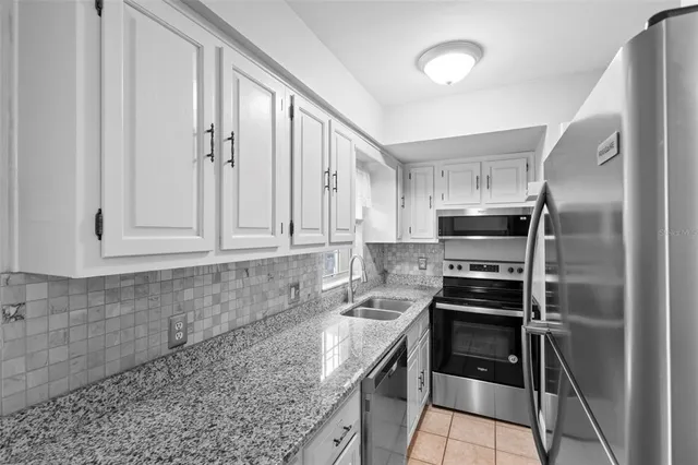 a kitchen with stainless steel appliances granite countertop a stove a refrigerator and a sink