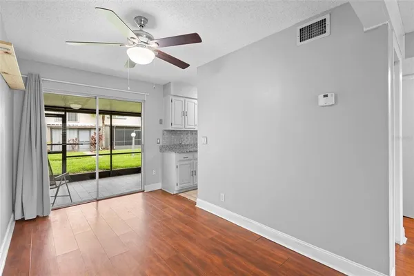 an empty room with ceiling fan and windows