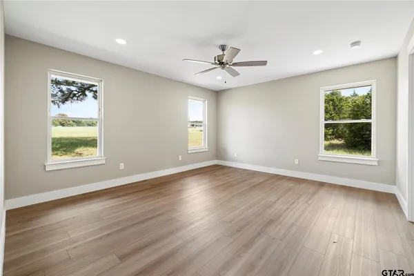 a view of empty room with wooden floor and fan