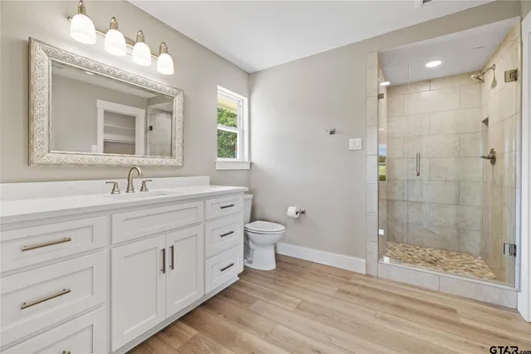 a bathroom with a double vanity sink a toilet and shower