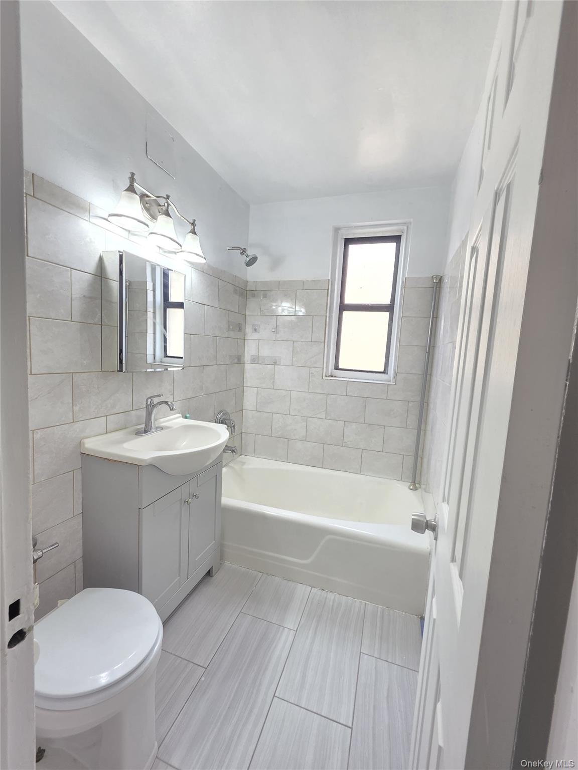 2640 Marion Avenue, Unit 6H Bronx, NY 10458 - Photo 12 of 14 a bathroom with a bathtub a sink a toilet a mirror and vanity