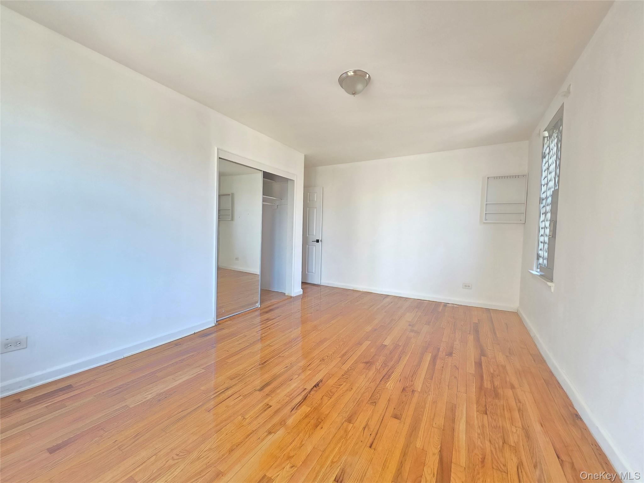 2640 Marion Avenue, Unit 6H Bronx, NY 10458 - Photo 9 of 14 a view of an empty room with wooden floor and a window