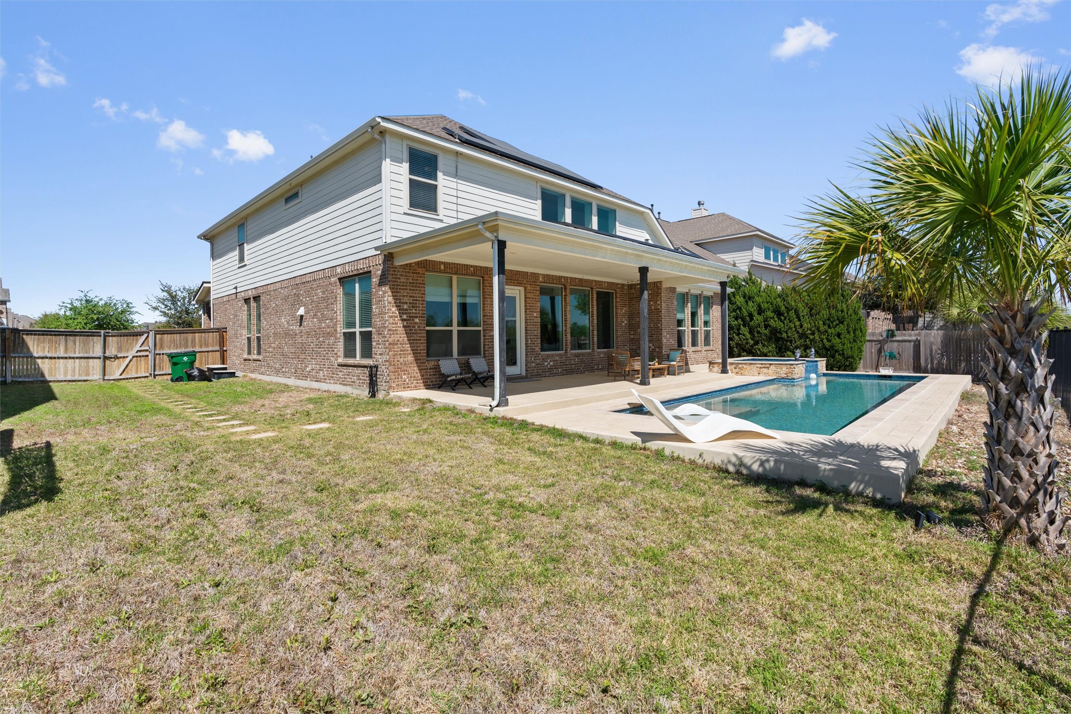 19325 Stembridge Run Pflugerville, TX 78660 - Photo 34 of 38 Rear view of house with a fenced backyard, roof mounted solar panels, a patio area, and brick siding
