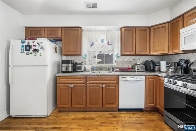 a kitchen with stainless steel appliances granite countertop a refrigerator sink and stove