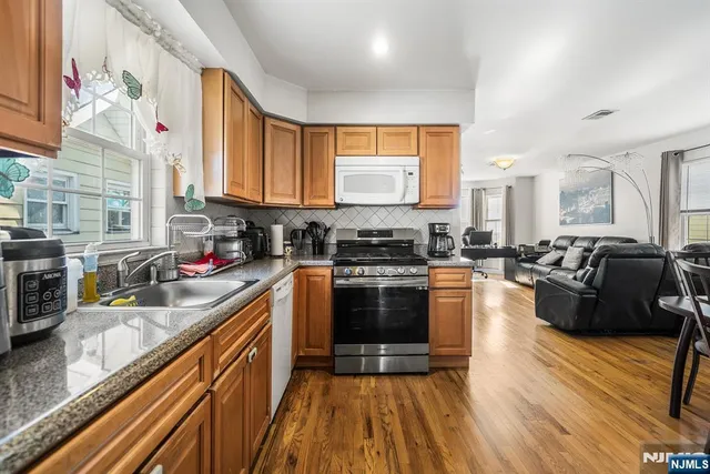 a kitchen with stainless steel appliances granite countertop wooden floors a stove a sink and a refrigerator