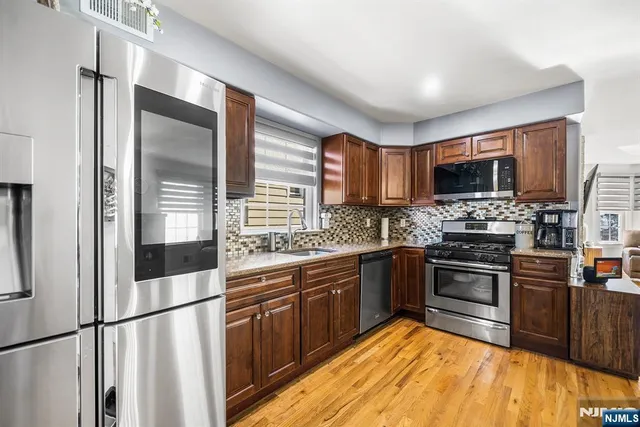 a kitchen with stainless steel appliances granite countertop a stove top oven a sink and a refrigerator
