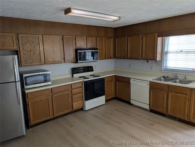 a kitchen with stainless steel appliances granite countertop a sink a stove a refrigerator with grey cabinets and wooden floor