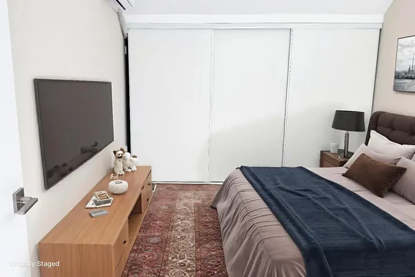 a bedroom with a bed and a flat tv screen on the dresser