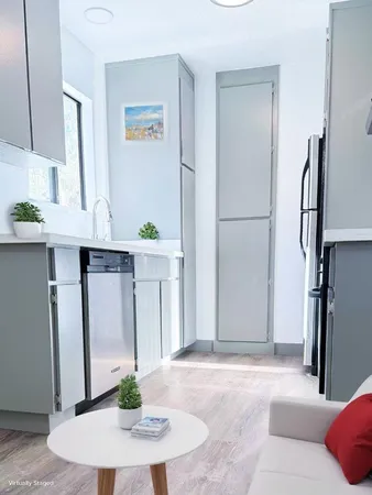 a living room with stainless steel appliances furniture a refrigerator and a wooden floor