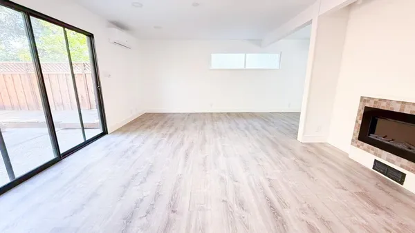 a view of empty room with wooden floor and fireplace