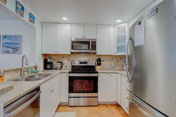 a kitchen with granite countertop white cabinets and stainless steel appliances
