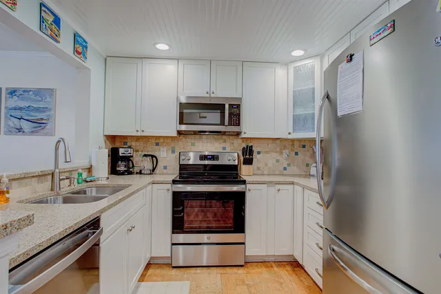 a kitchen with granite countertop white cabinets and stainless steel appliances